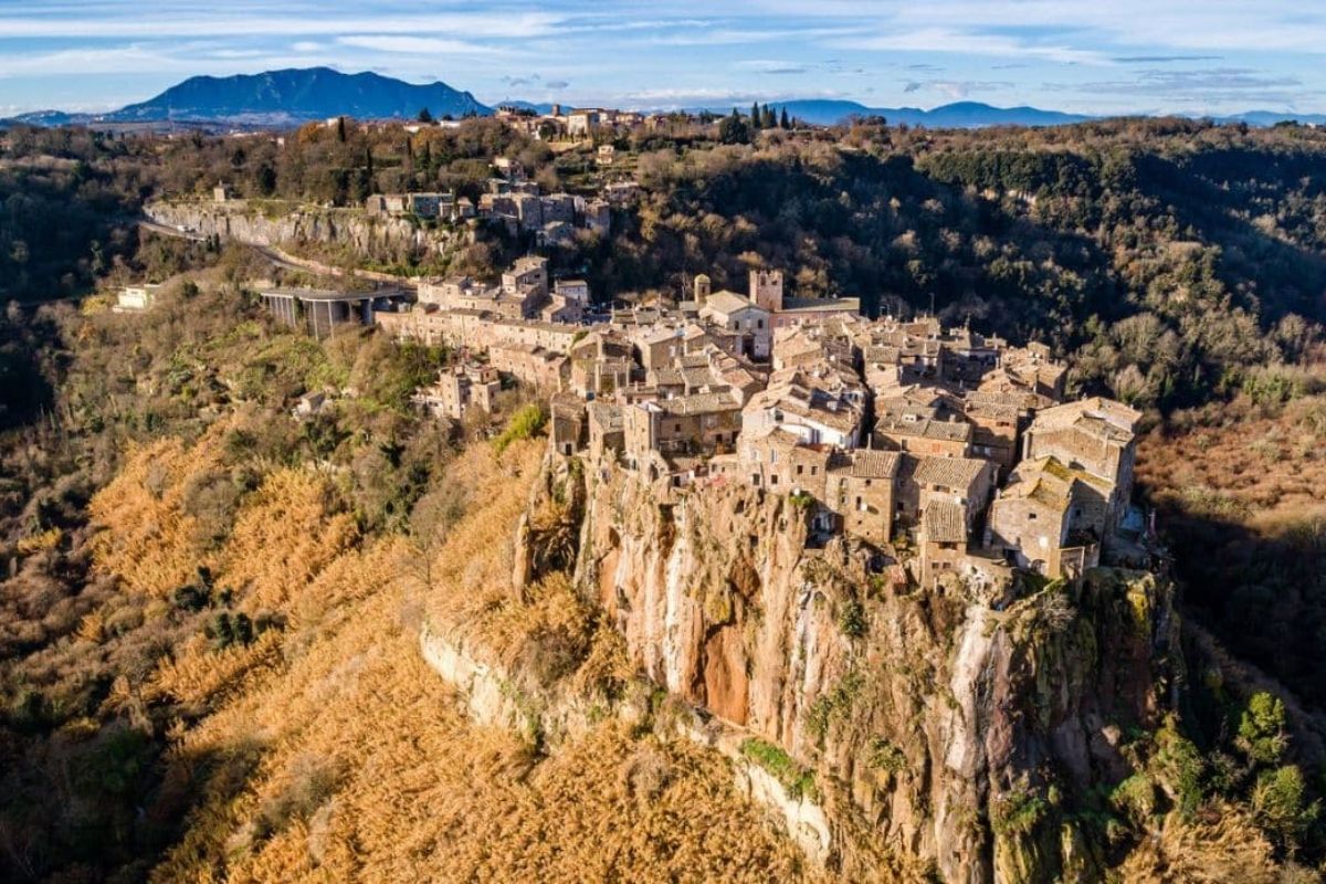 Veduta panoramica di Calcata con artisti al lavoro, evidenziando il borgo e la rupe di tufo